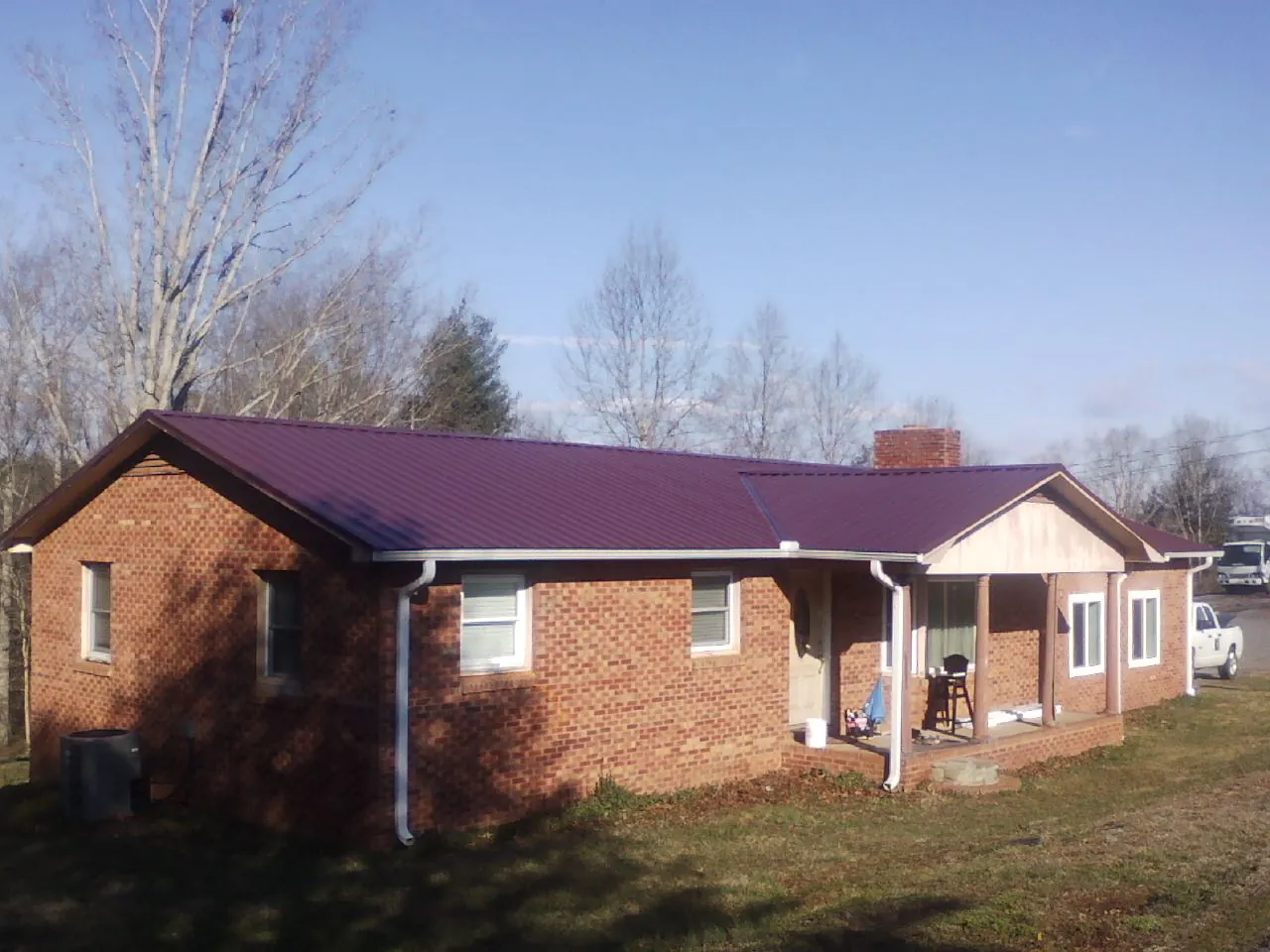 Burgundy metal roof on a brick ranch home with a new addition in Spring Lake