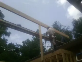 Carpenter setting a ridge beam over a new addition frame — Ice Dam Removal by Roofing Brothers in Spring Lake