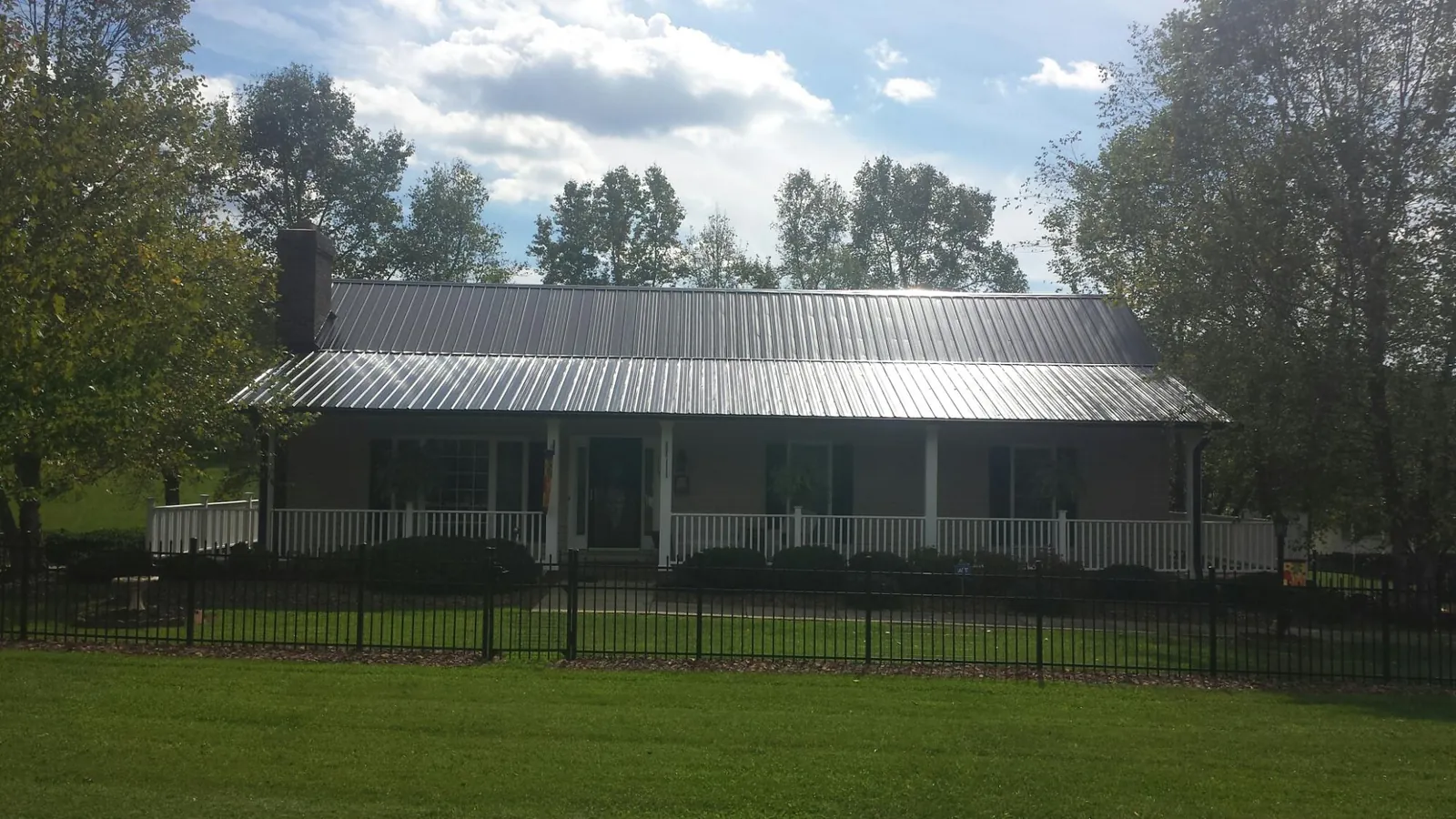 Gray metal roof on a brick ranch with a full width front porch — Gutter Guard Installation work by our crew in Spring Lake