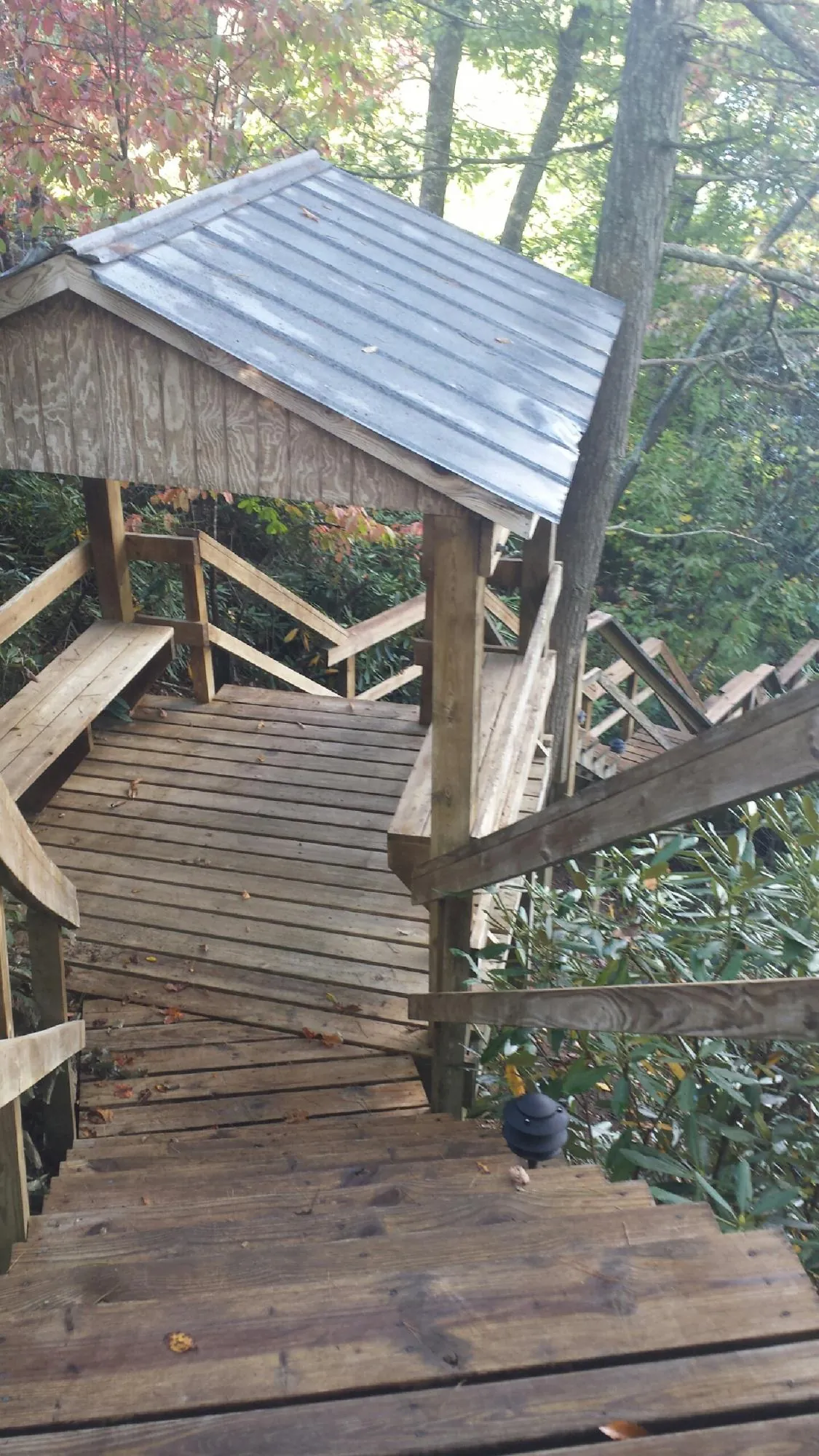 Metal roofed shelter over wooden steps on a wooded walkway — Skylight Repair & Installation work by our crew in Spring Lake