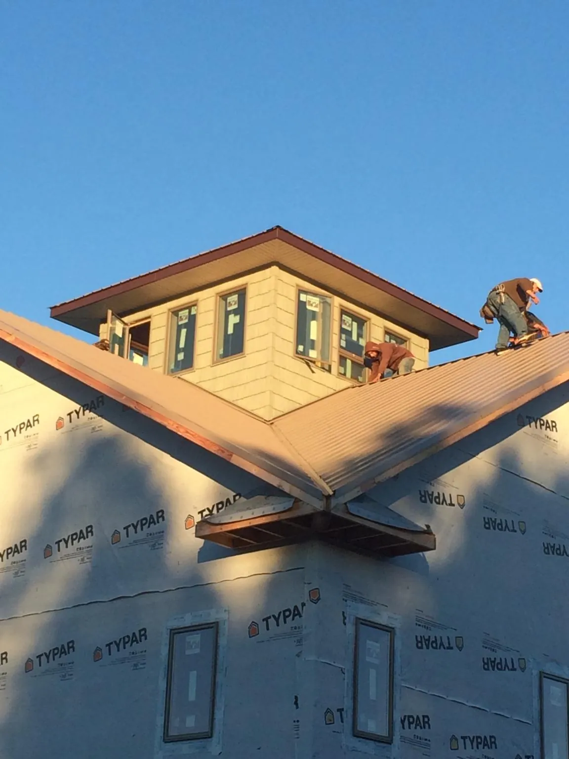 Roofers working around a rooftop cupola on a new metal roof at sunset — Roof Waterproofing in Spring Lake by Roofing Brothers